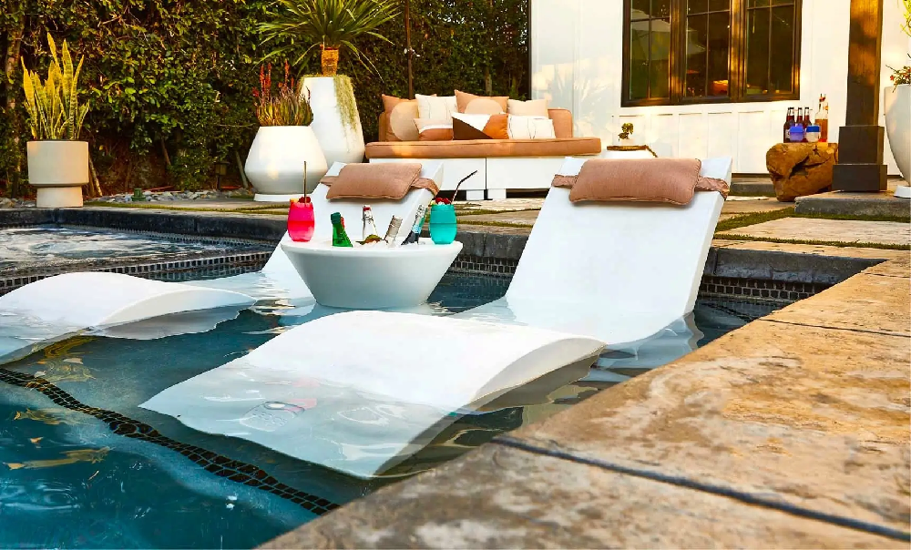 White in-pool chaise lounges paired with an ice bin table creating an elegant swim-up entertaining space.